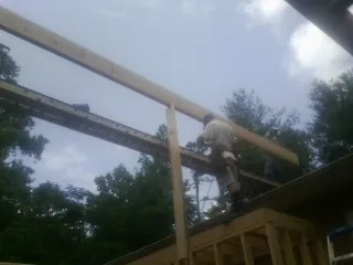 Carpenter setting a ridge beam over a new addition frame — Ice Dam Removal by Roofing Brothers in Underwood