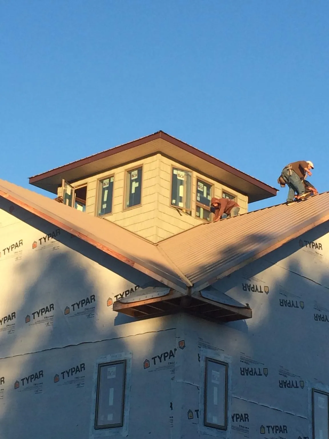 Roofers working around a rooftop cupola on a new metal roof at sunset — Roof Waterproofing in Underwood by Roofing Brothers